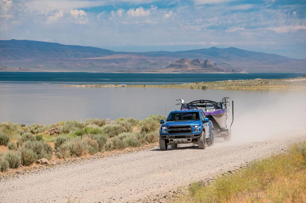 A Ford Raptor towing the Tige alongside a lake