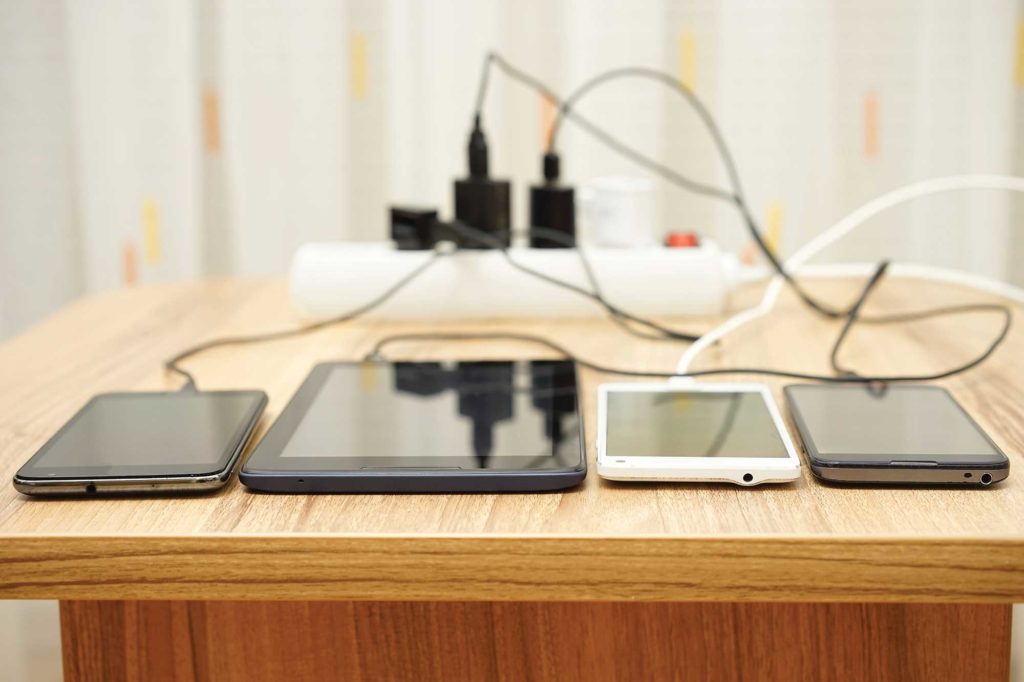 Multiple phones and tablets plugged into a power strip