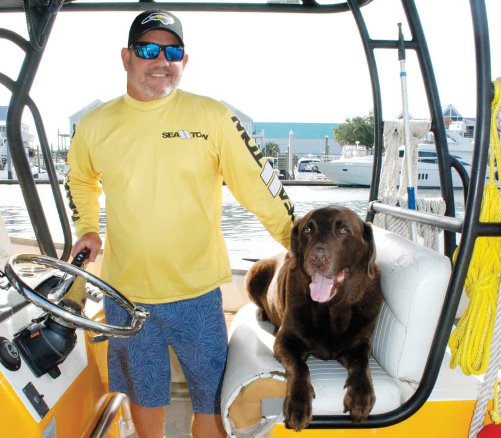 Sea Tow captain Scott Collins with his chocolate lab on a boat