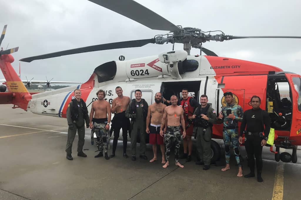 Coast Guard helicopter crew standing with fishermen after rescue