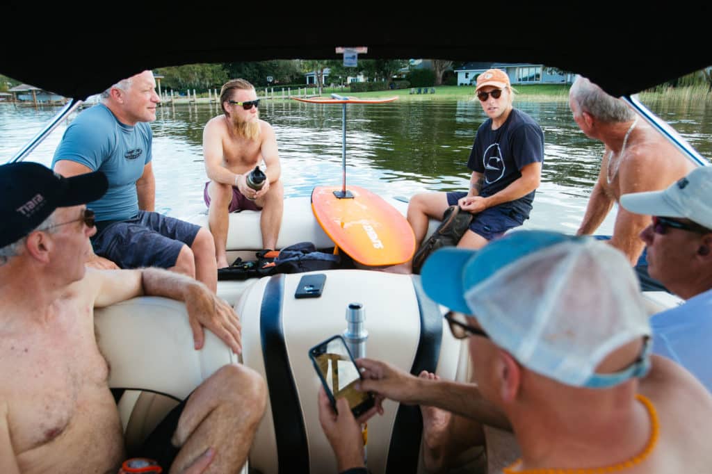 Skiers and wake foilers talking on boat