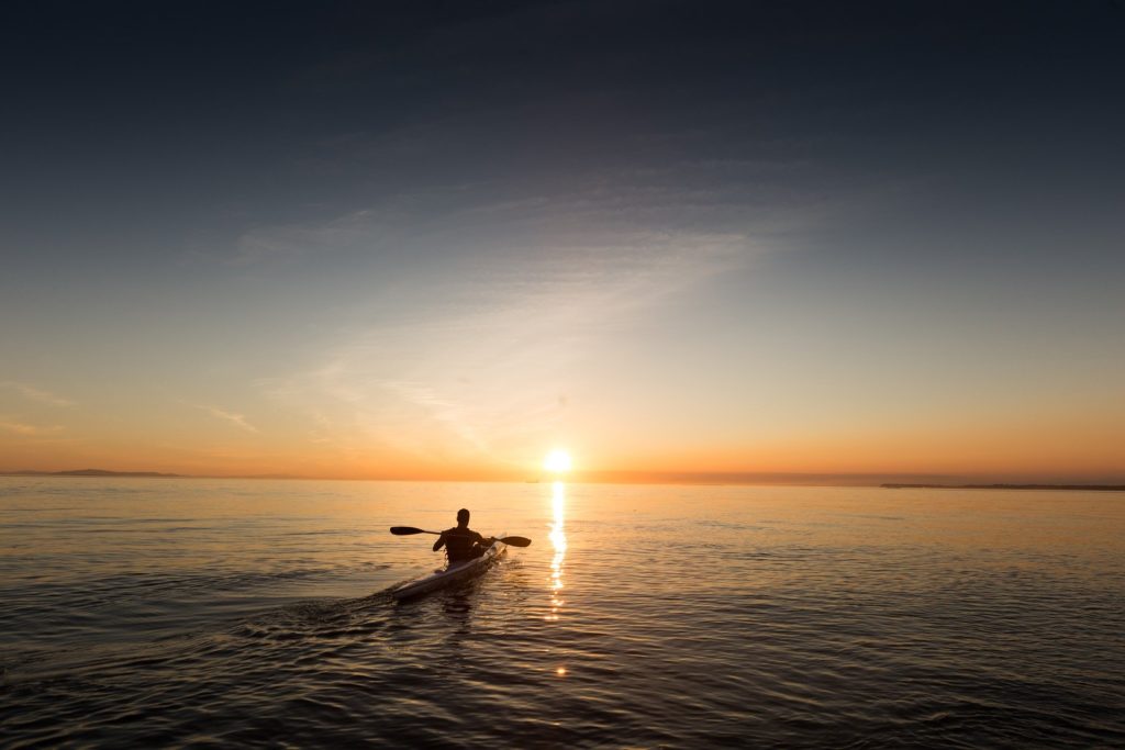 Kayaker paddling at sunset