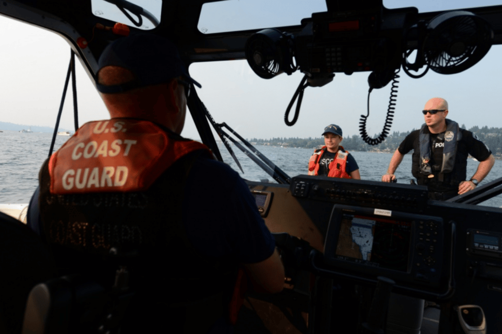 Chief Petty Officer Jeff Wildes, U.S. Coast Guard Station Seattle, looks out for boating traffic while Petty Officer 3rd Class Maggie Nicol, also from Station Seattle, and Sgt. Mike Seifert from the Mercer Island Police Department keep and eye on some pas